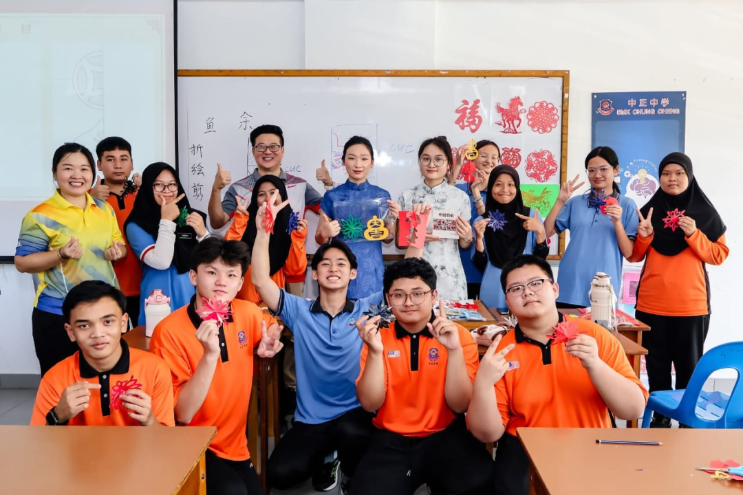“我爱砂拉越”活动参加者手持红色剪纸作品合影